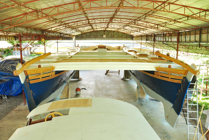 Large blue catamaran under shelter, looking at the stern