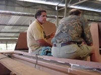 James sitting on an unfinished hull in workshop