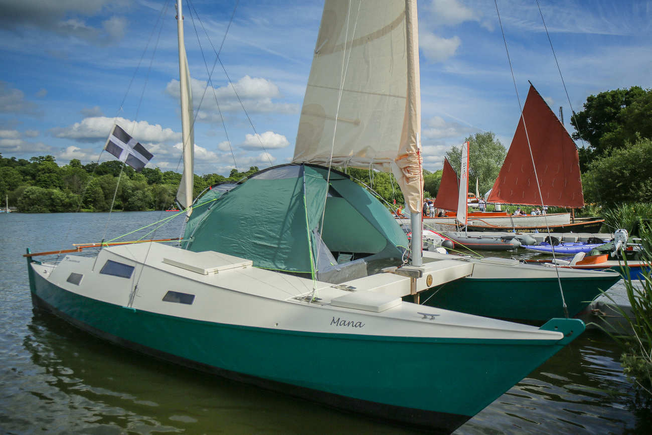 Wharram Mana 24 with white and teal hulls, with deck tent on board
