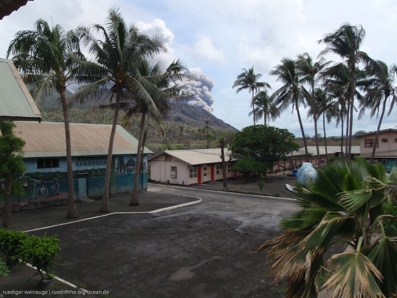 Village with erupting volcano in the distance