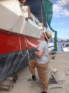 Bryce installing new beamlashings, using a rope loop which he is standing in to pull them tight