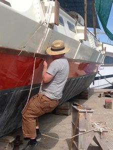 Bryce installing new beamlashings, using a rope loop which he is standing in to pull them tight